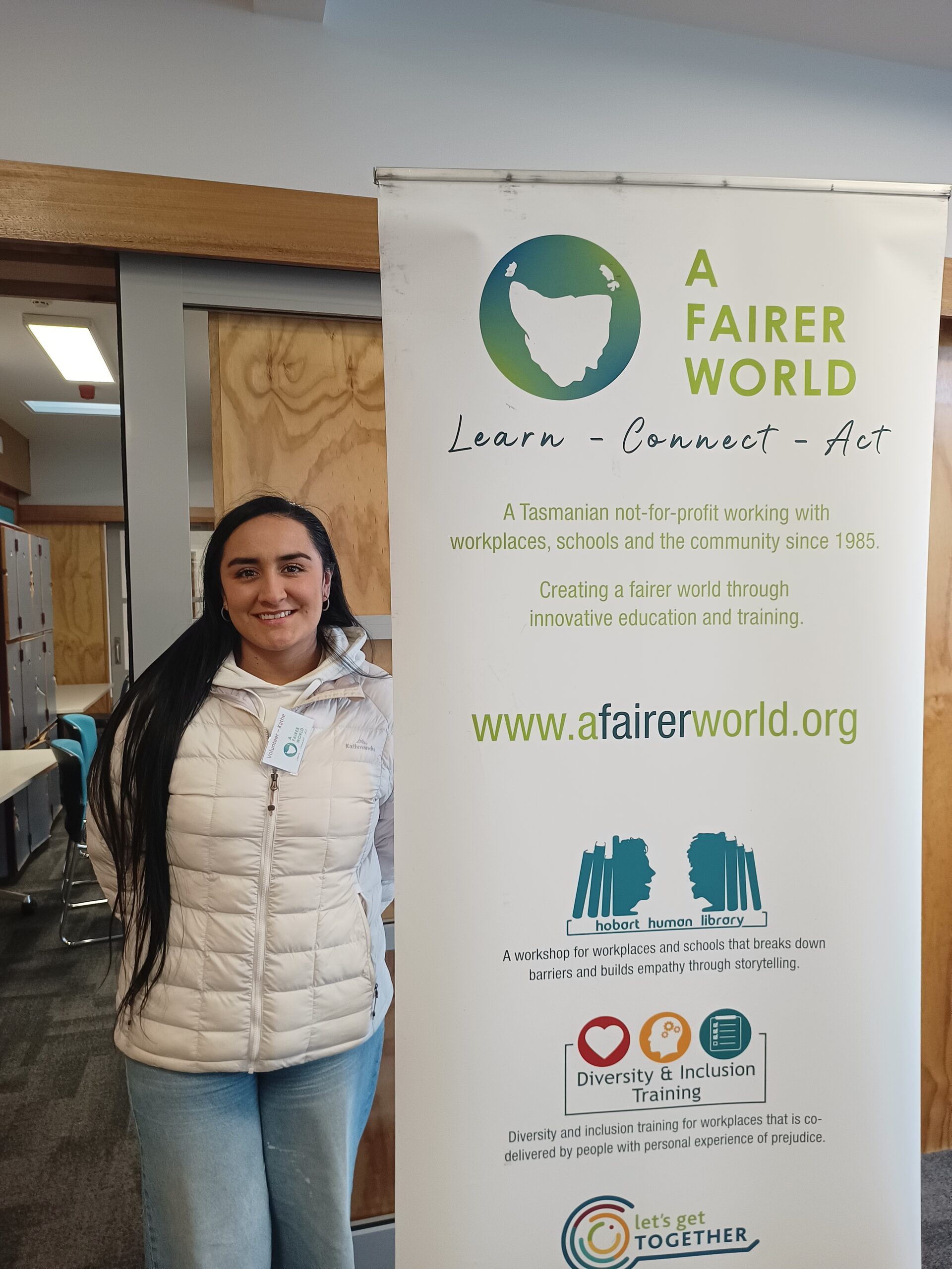 Kathe standing next to the A Fairer World banner