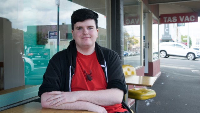 Photo of Sam sitting outside a restaurant.